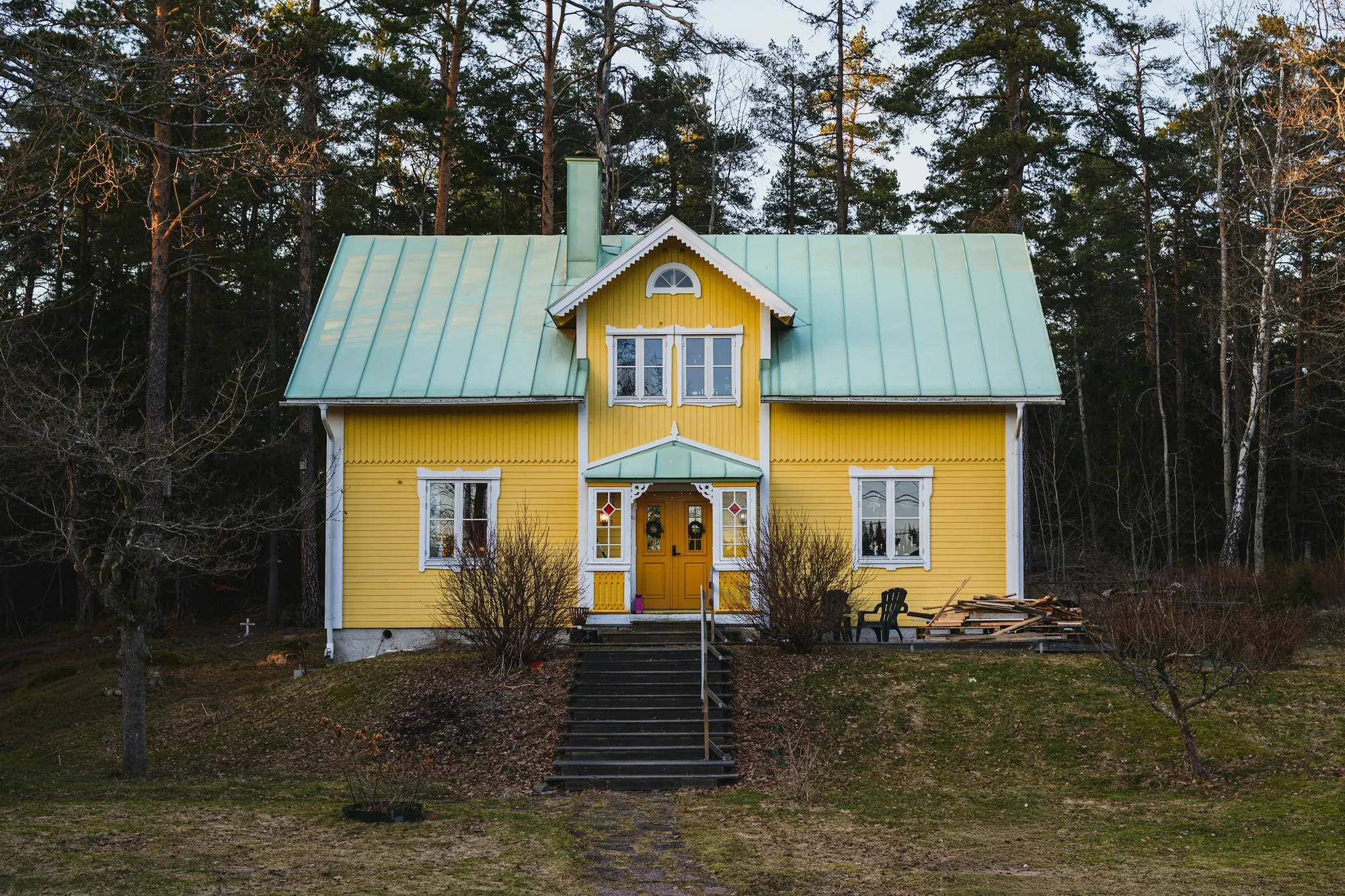 Gult trähus med grönt tak i skogen