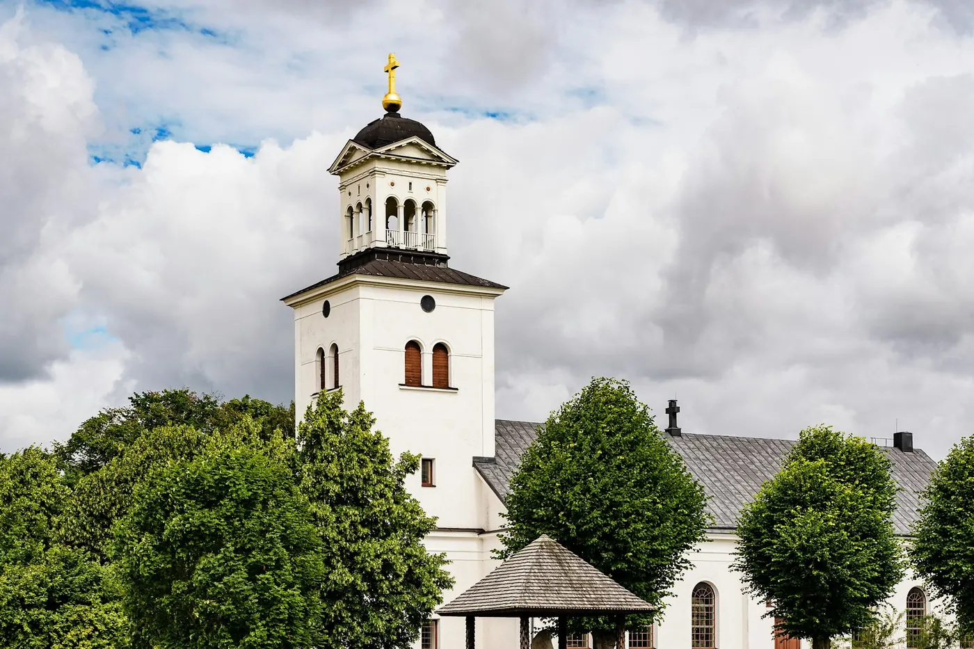 Vit kyrka med torn bakom ett sädesfält